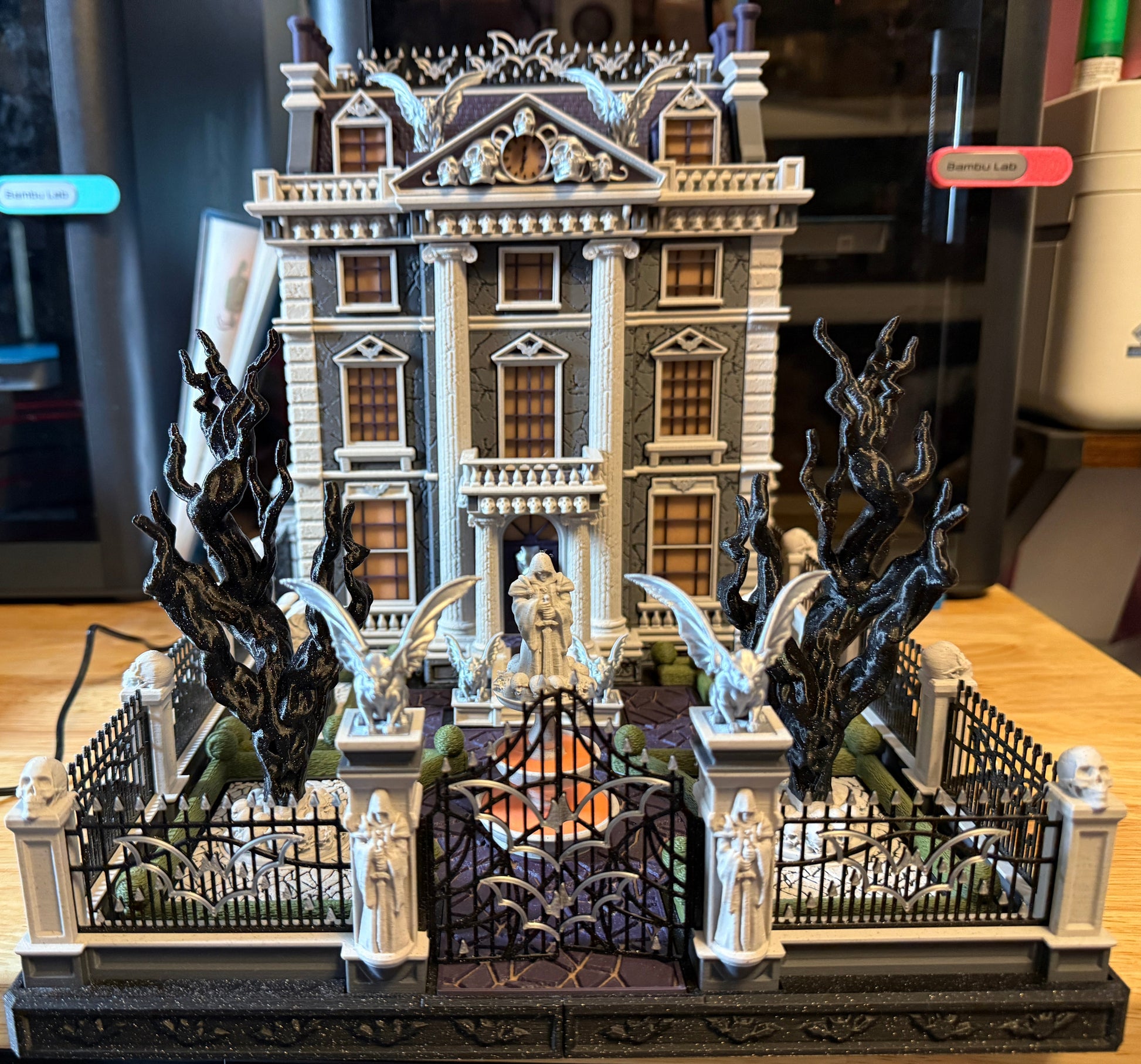 Detailed model of a haunted house with dragons and ghosts on a wooden surface.